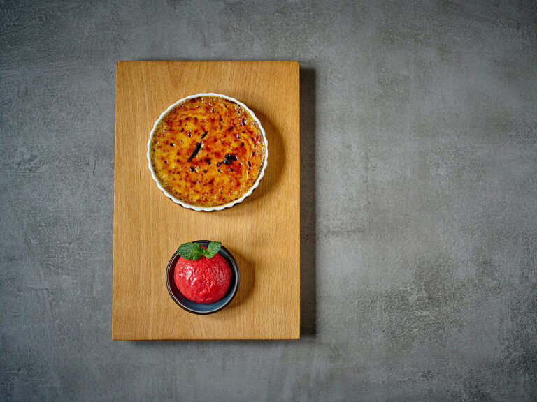 Detailaufnahme ein leckeren Nachspeise, bestehend aus Crème Brûlée sowie einem Sorbeteis.