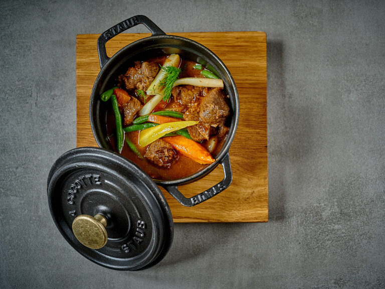 Ein Eintopf steht auf einem Holzbrett.